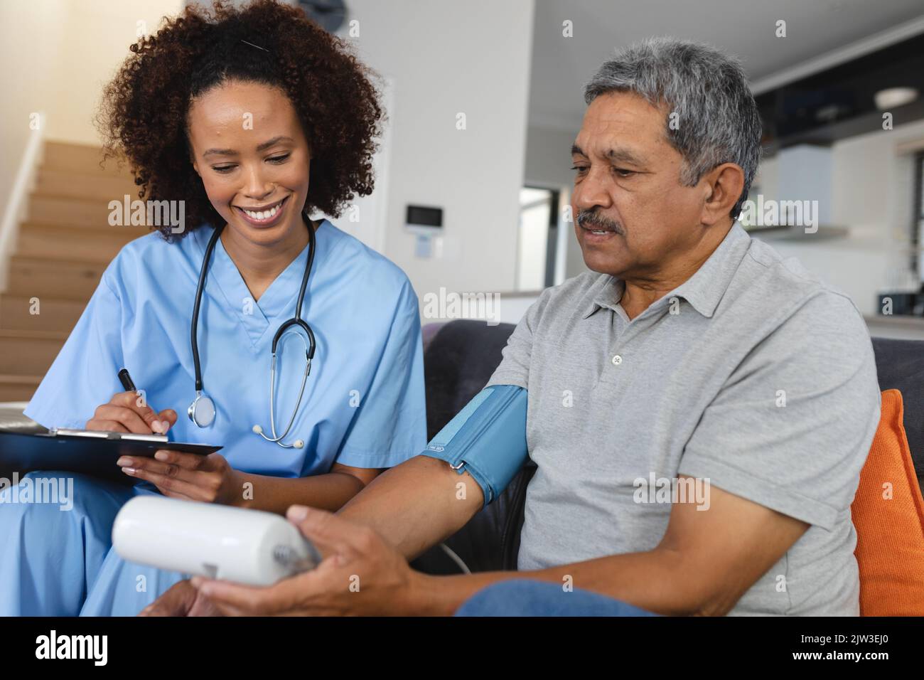 Homme de race mixte senior avec une femme médecin visitant à la maison prenant de la tension artérielle Banque D'Images