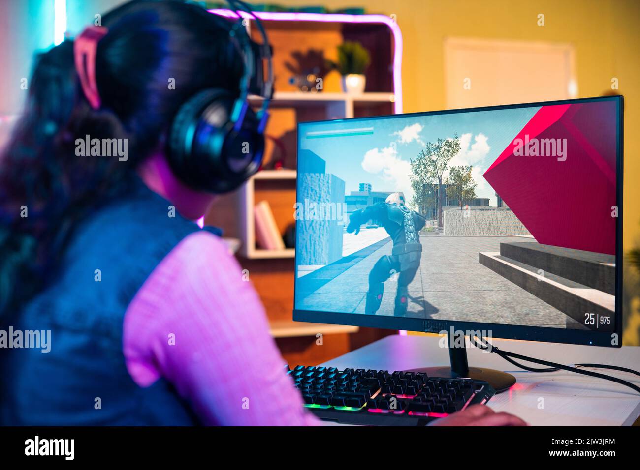 prise de vue en bandoulière d'un joueur jouant à un jeu vidéo en ligne sur un ordinateur en parlant sur un casque à la maison - concept de compétition, de divertissement et de professionnel Banque D'Images