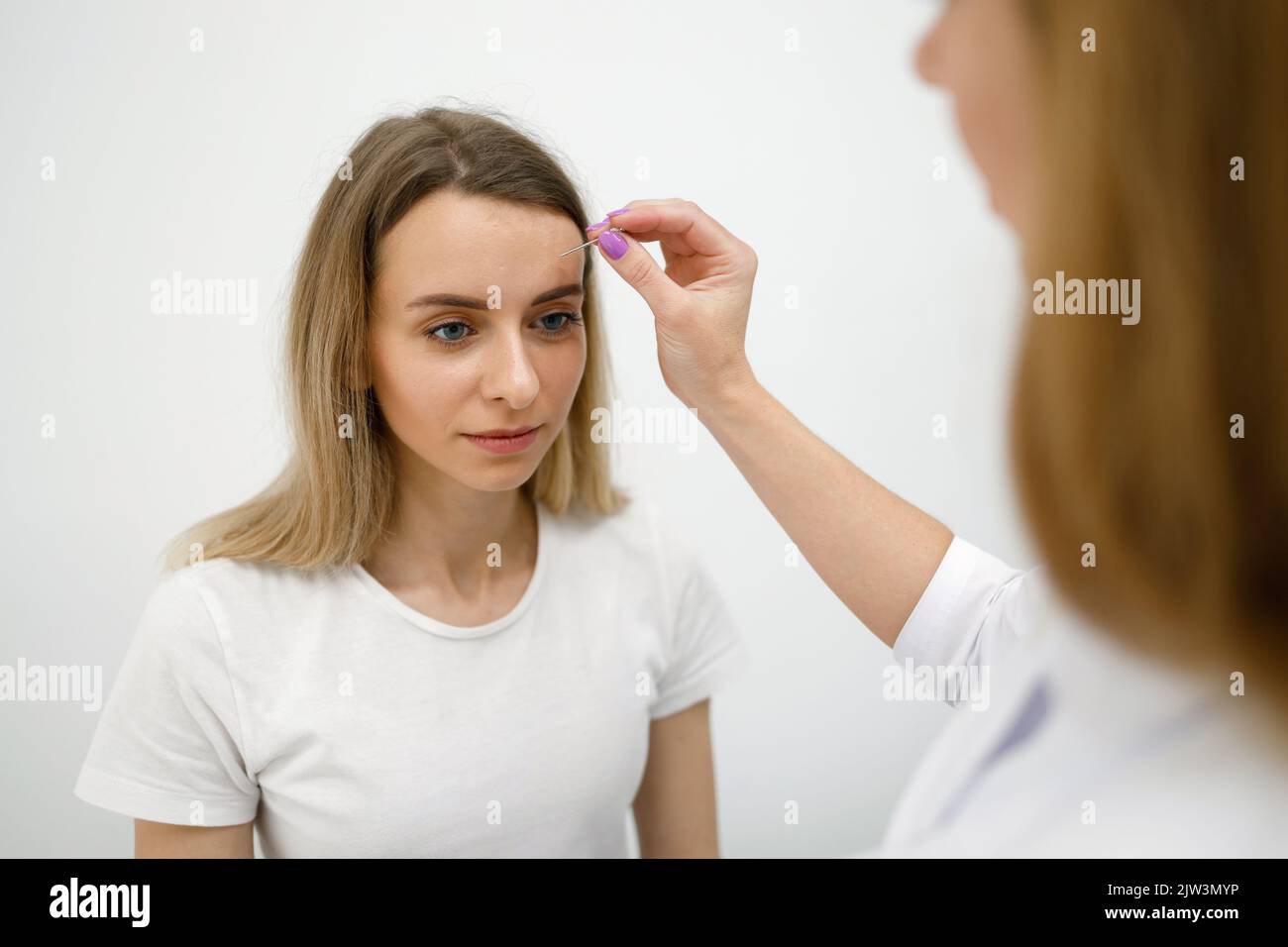Le médecin neurologue vérifie la sensibilité de la patiente à l'aide d'une aiguille spéciale. Femme à l'examen en clinique Banque D'Images