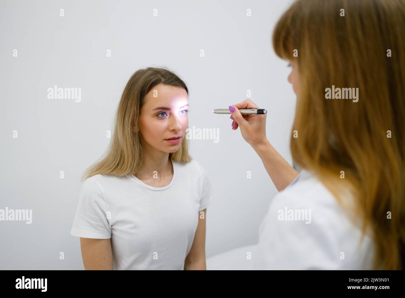 Le médecin effectue un test de sensibilité des pupilles des yeux en  éclairant la lampe de poche dans l'œil du patient Photo Stock - Alamy