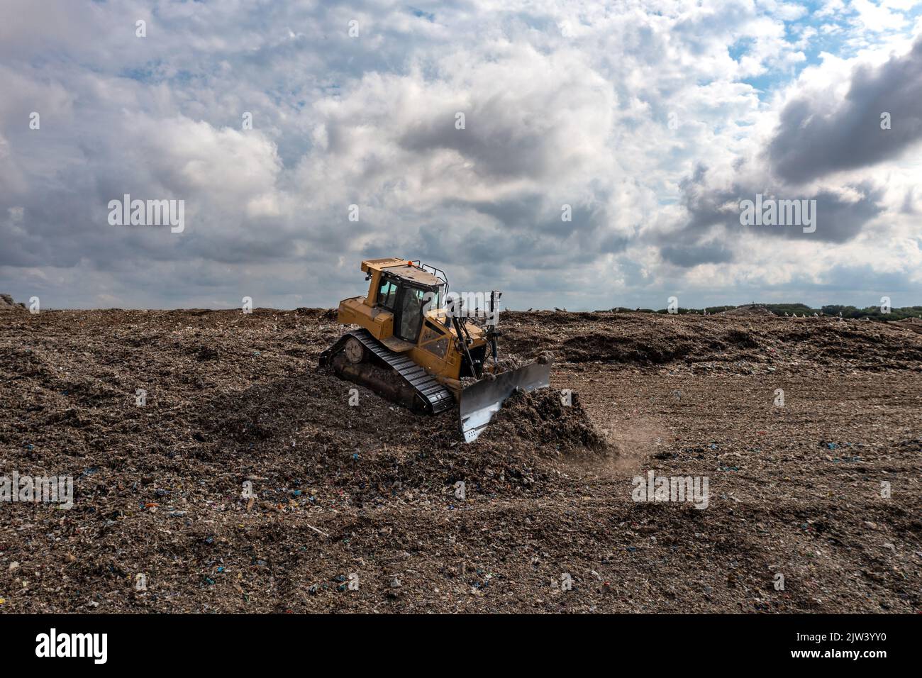 Une machine à bulldozer qui déplace les déchets et les ordures ménagères sur un grand tas de décharges sanitaires Banque D'Images
