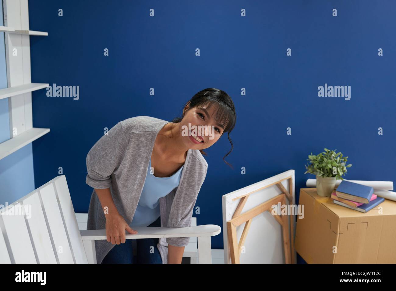 Jeune femme asiatique attrayante emballage ses affaires et souriant à la caméra heureux tout en déplaçant de l'appartement Banque D'Images