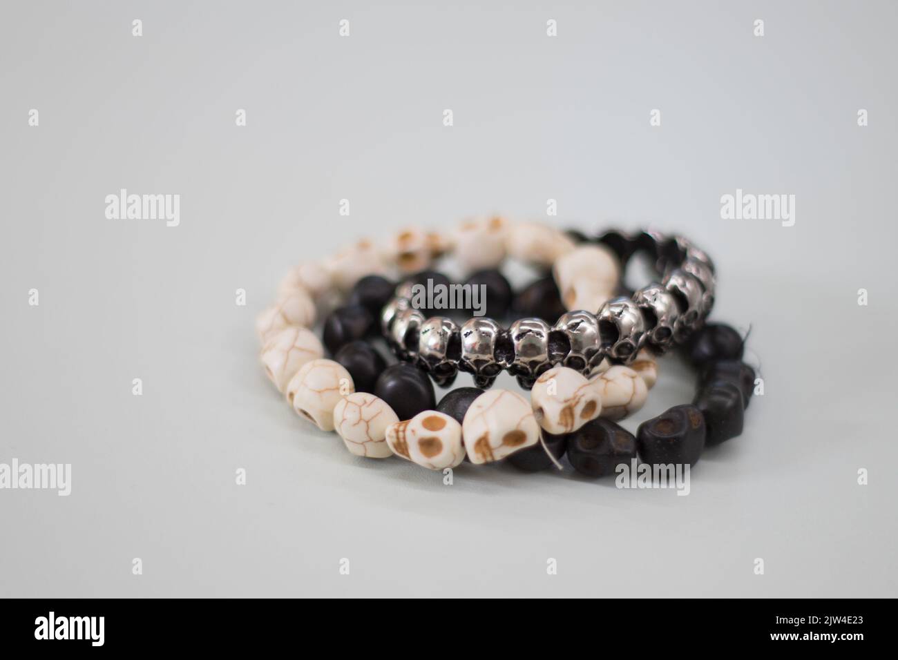 Gros plan de bracelets avec de petites perles en forme de crâne sur une surface grise Banque D'Images