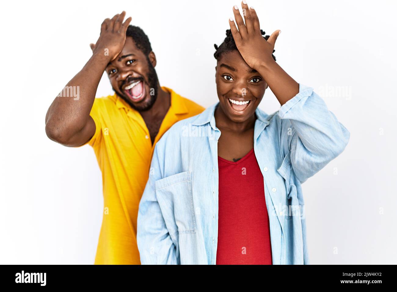 Un jeune couple afro-américain portant des vêtements décontractés surpris de la main sur la tête pour erreur, souvenez-vous de l'erreur. oublié, mauvais concept de mémoire. Banque D'Images Un jeune couple afro-américain portant des vêtements décontractés surpris de la main sur la tête pour erreur, souvenez-vous de l'erreur. oublié, mauvais concept de mémoire. Banque D'Images