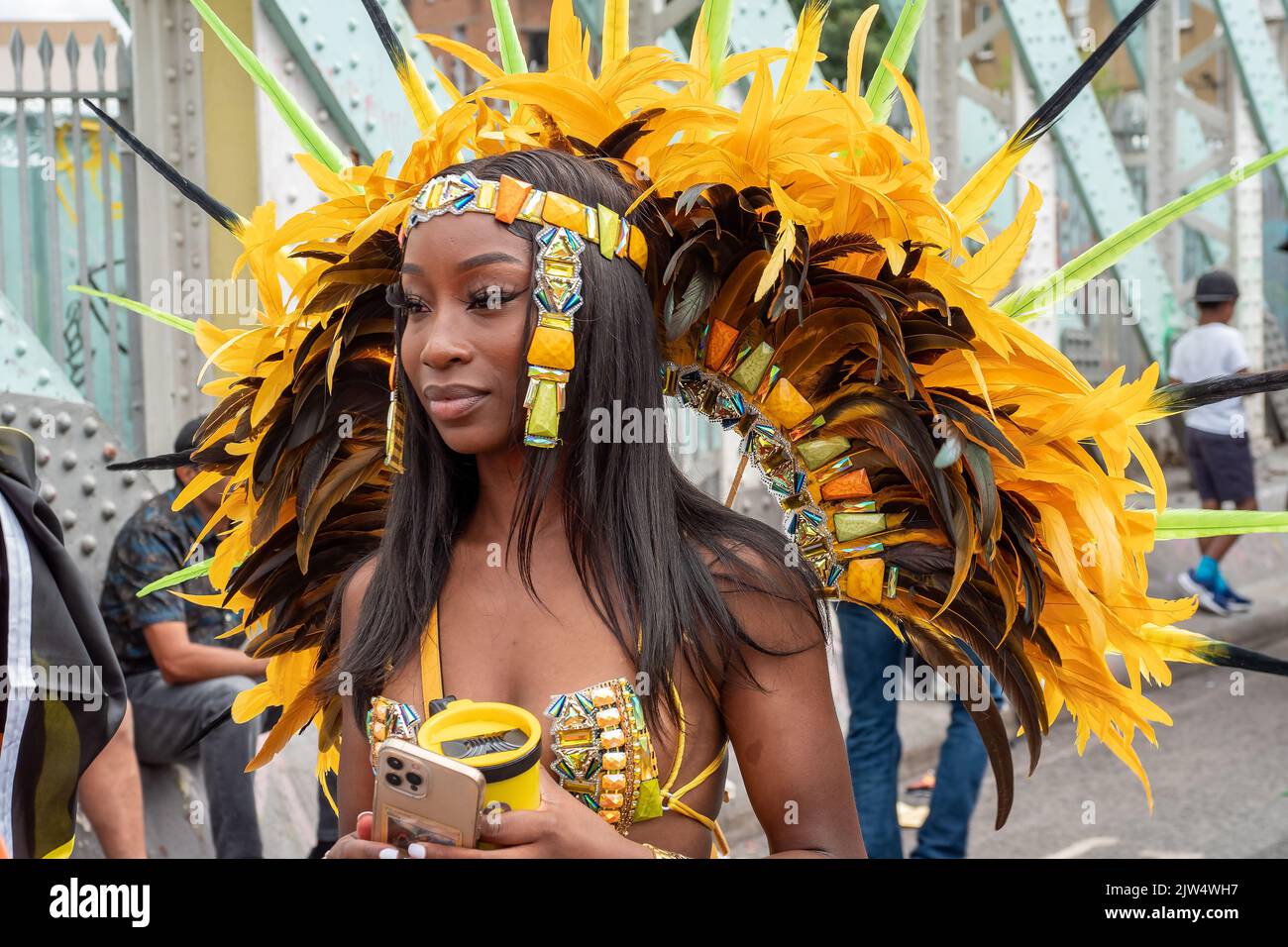 Londres, Angleterre, Royaume-Uni - 29 août 2022: Jeune femme noire vêtue de plumes jaunes dans les rues, à Notting Hill Banque D'Images