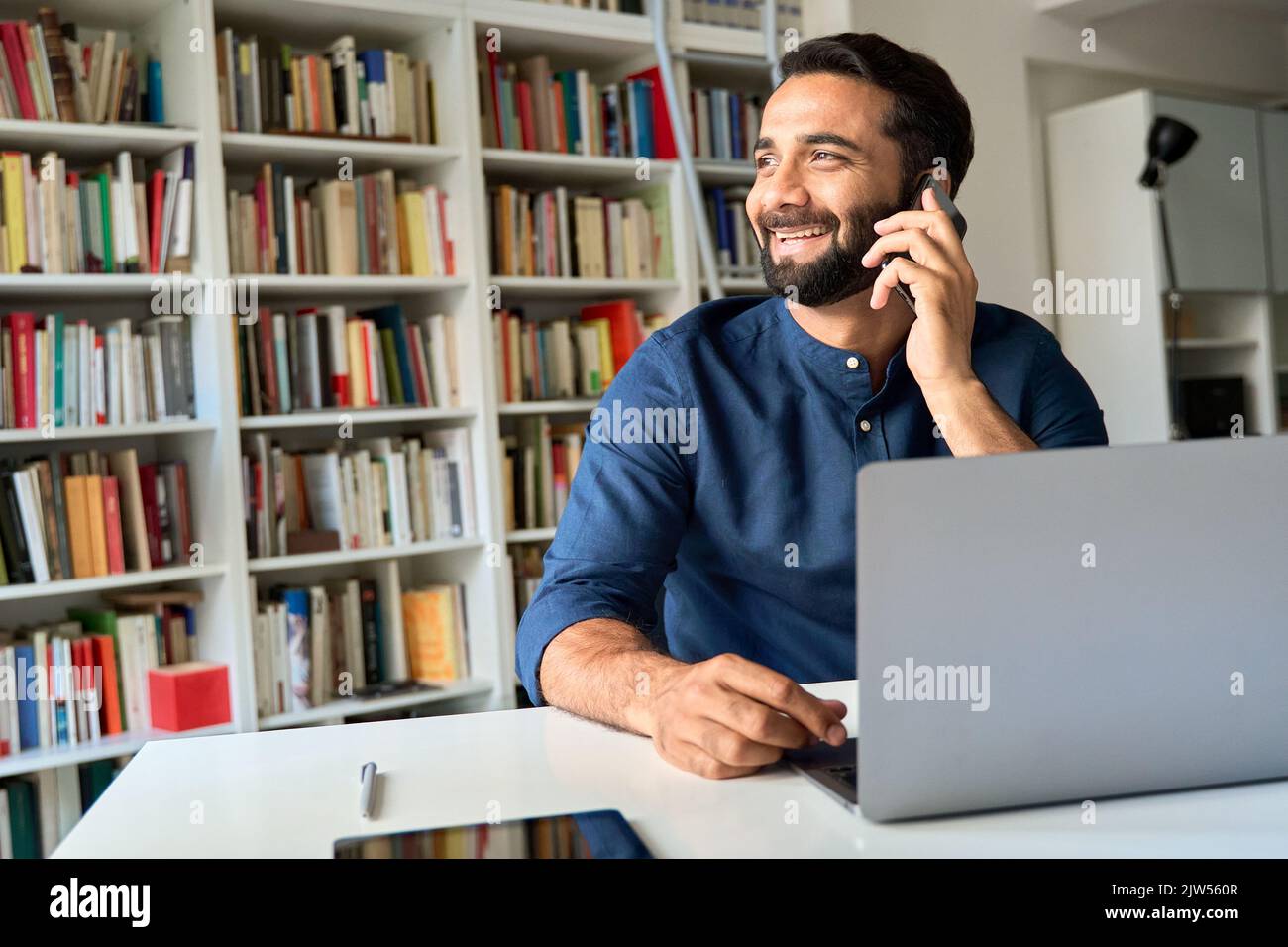 Homme d'affaires indien souriant assis au bureau parlant au téléphone pour passer un appel. Banque D'Images