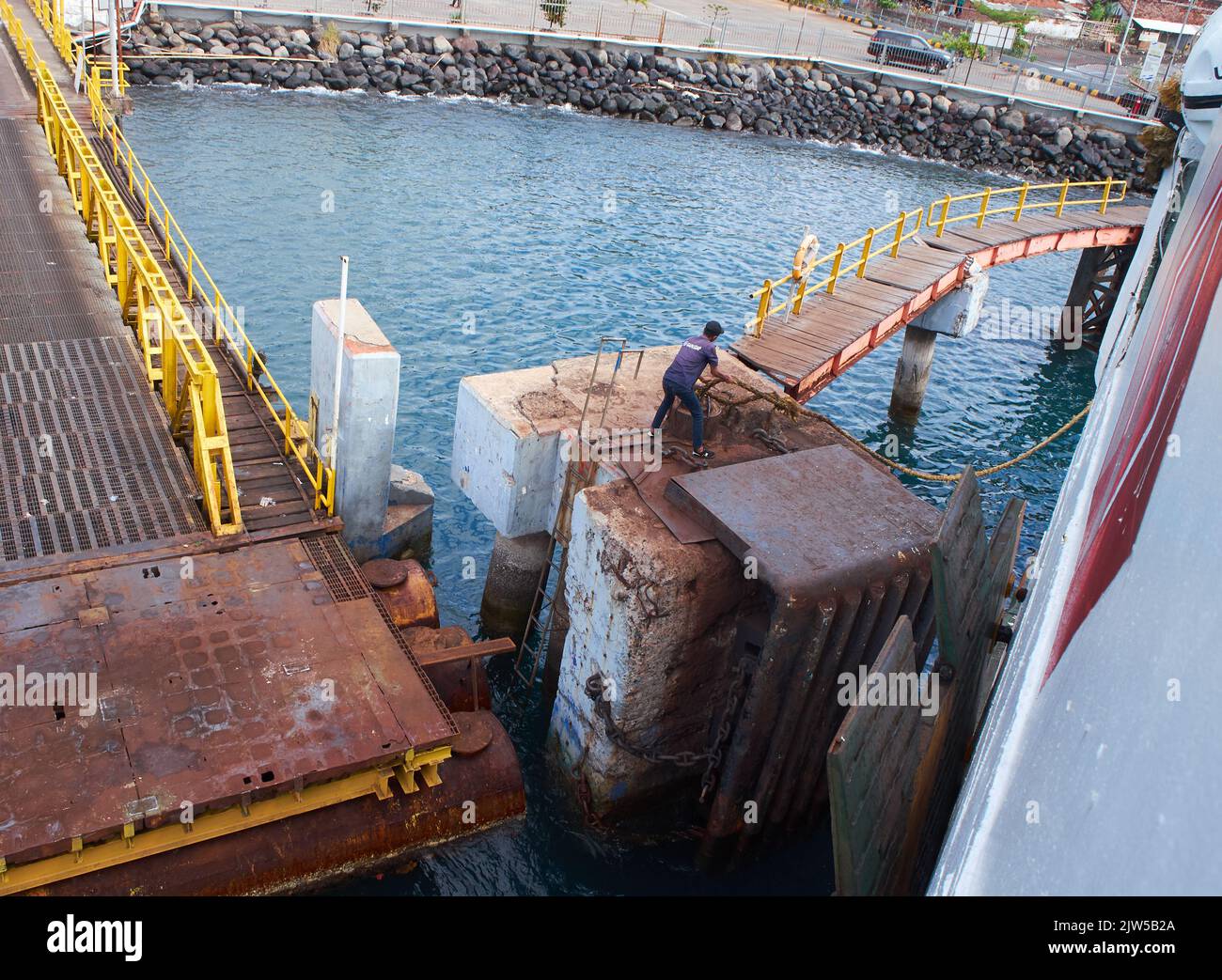 Un agent du port retire la corde d'ancrage d'un traversier au port de Ketapang qui traversera le détroit de Bali Banque D'Images