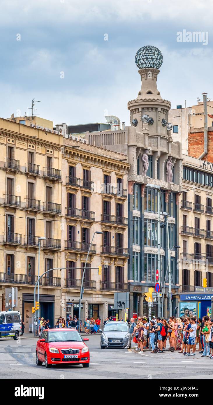 Une foule de gens attend de traverser la rue sur la Plaza de Catalogne. La célèbre architecture des bâtiments est vue en arrière-plan. Banque D'Images