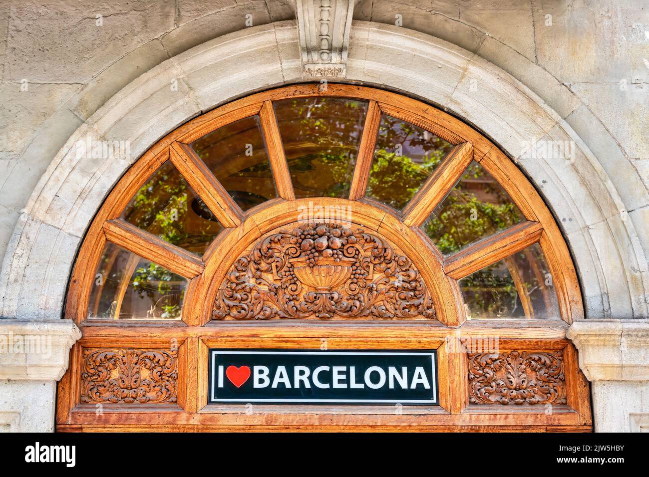Une arche architecturale avec des sculptures en bois décorant une entrée de bâtiment. Il y a un signe lisant J'aime Barcelone Banque D'Images