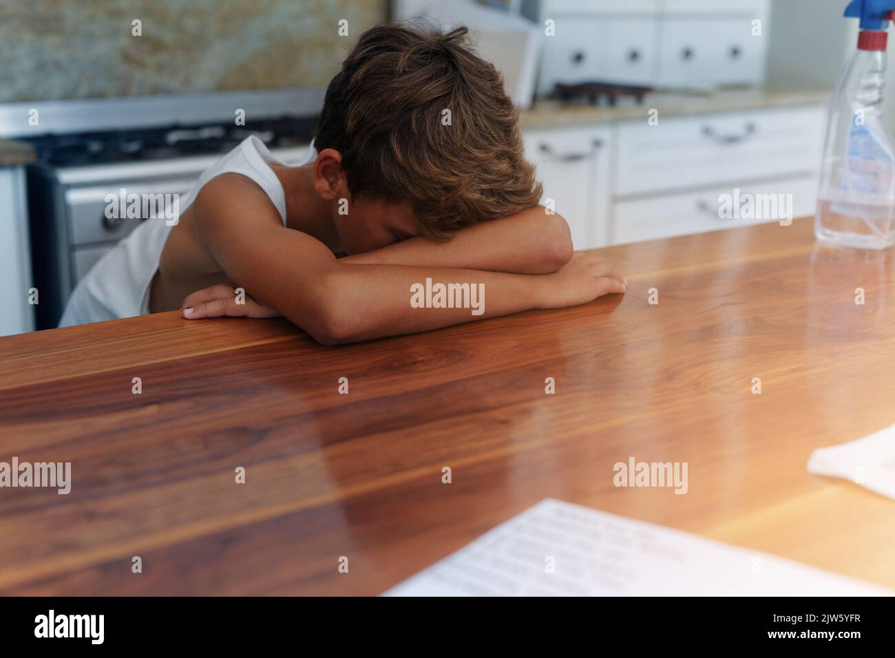 HES se sentant un peu bleu aujourd'hui. Un jeune garçon allongé avec sa tête sur une table. Banque D'Images