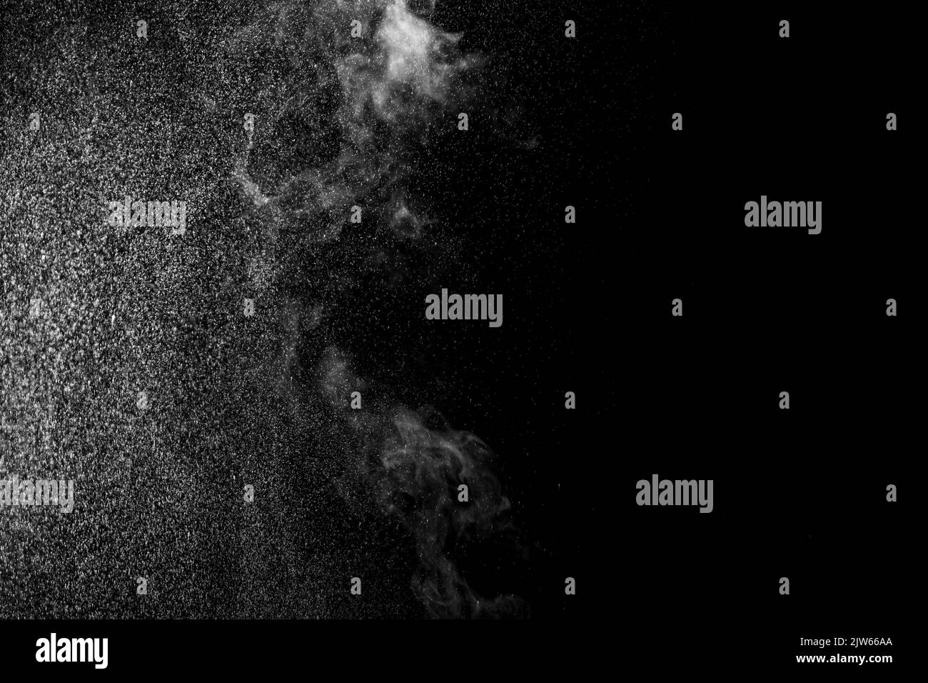Vapeur blanche bouclés qui s'élève et projection d'eau dans différentes directions isolée sur fond noir. Évaporation du liquide et du condensateur Banque D'Images