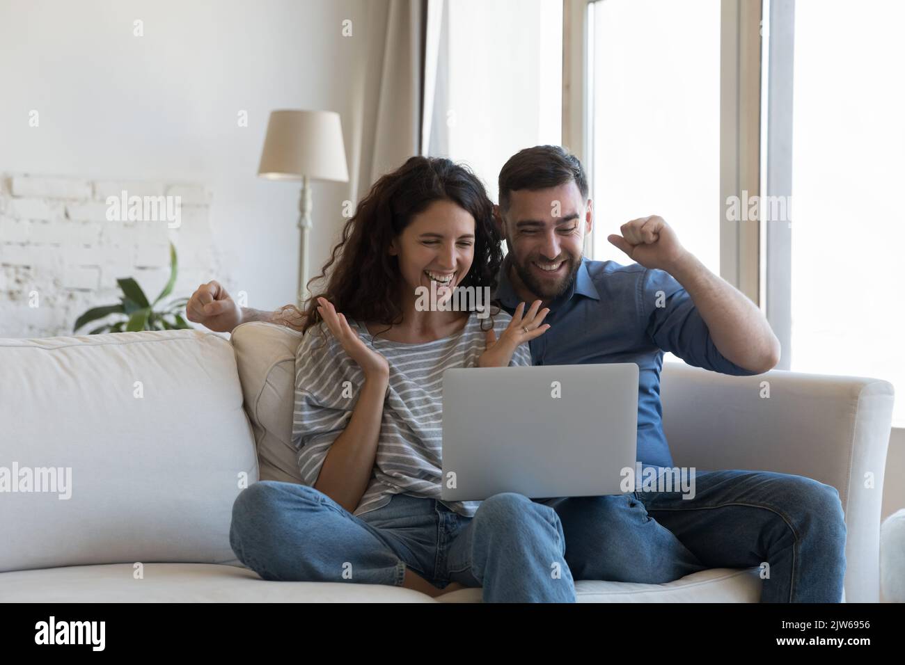 Un couple lit son e-mail sur son ordinateur portable, obtient des nouvelles fantastiques, célèbre le succès Banque D'Images