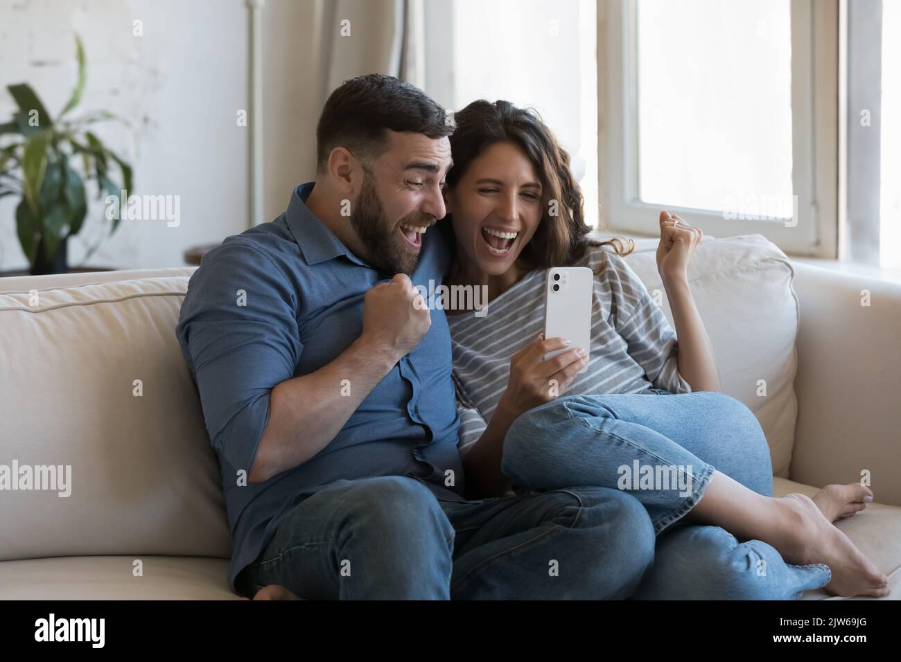 Couple se sentent heureux lire de grandes nouvelles sur le téléphone portable Banque D'Images