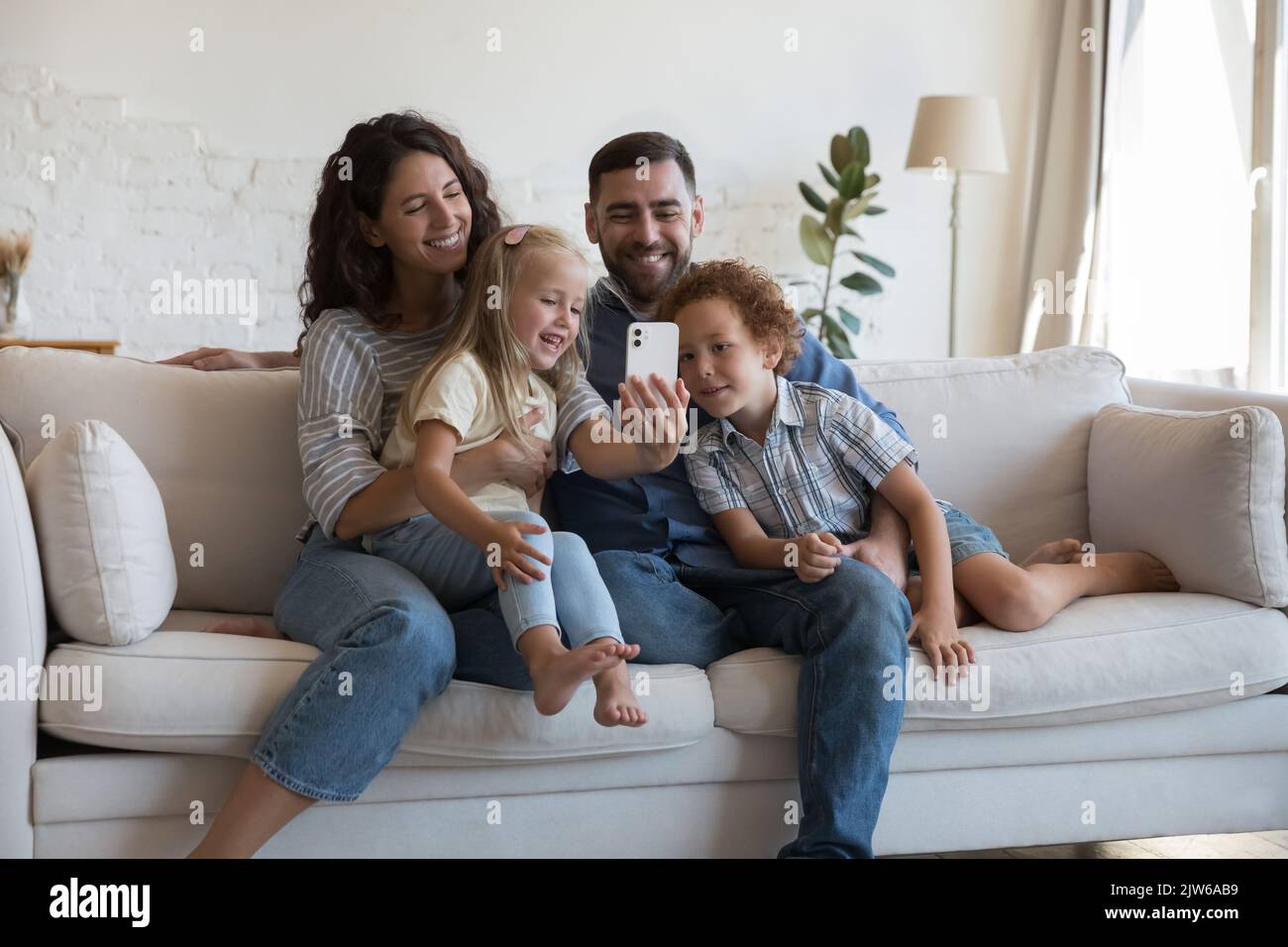 Une famille heureuse avec de petits enfants adorables passe des vacances à l'aide d'un smartphone Banque D'Images