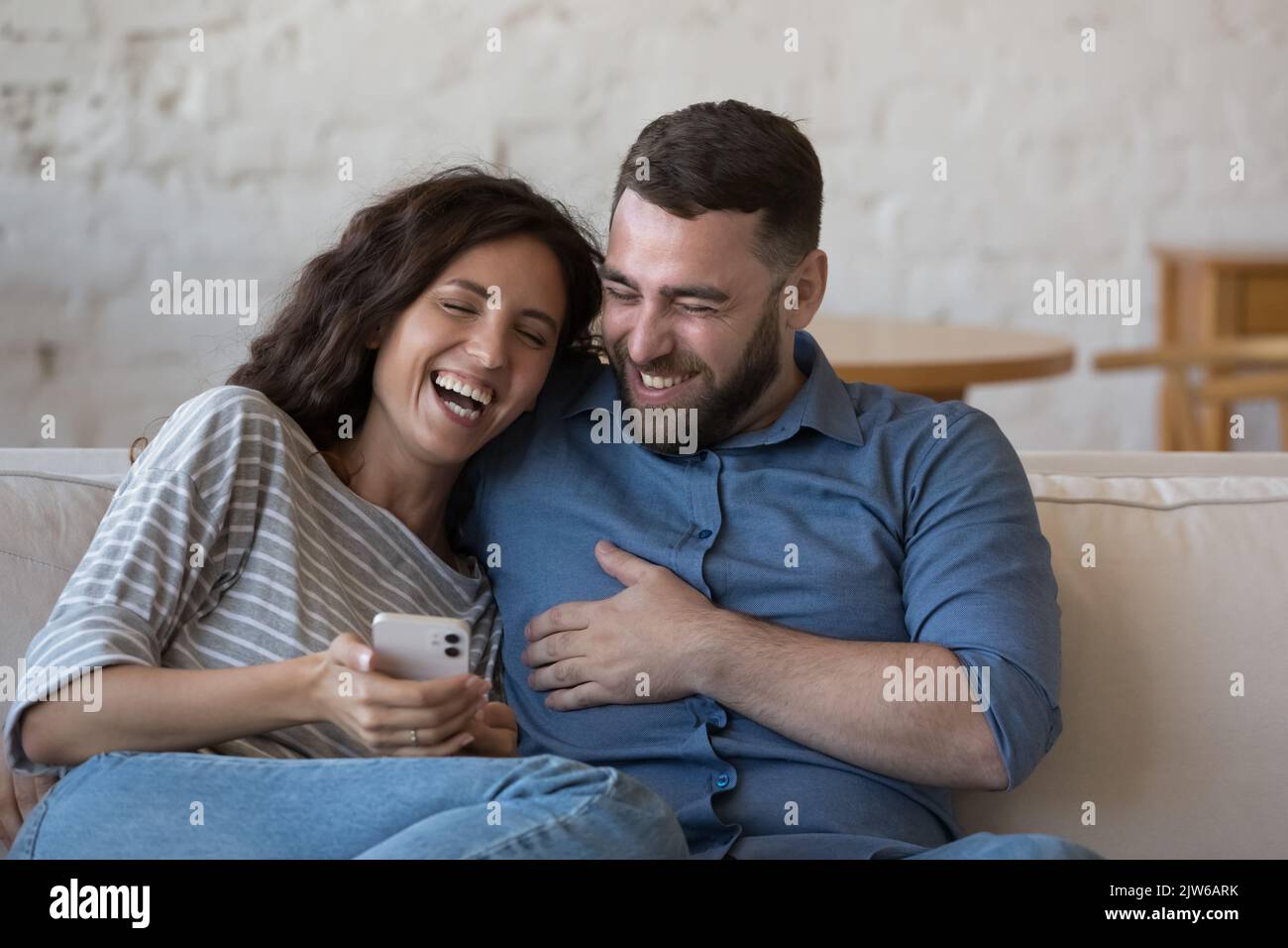 Couple riant sans souci regarder des vidéos sur Internet utiliser le téléphone portable Banque D'Images