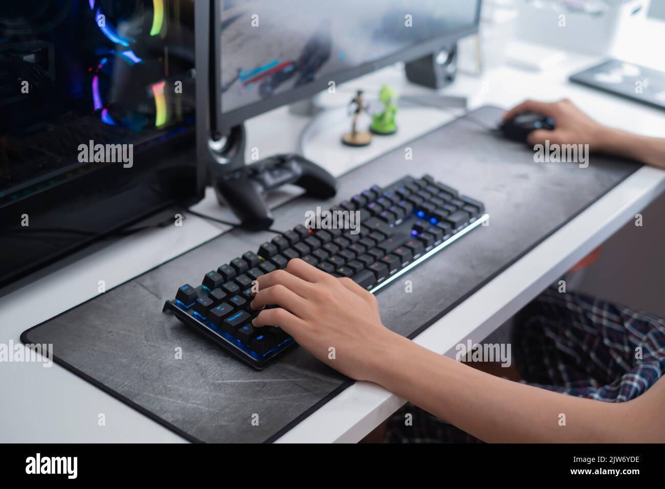 mise au point sélective d'un adolescent mains jouant sur un ordinateur de jeu, avec un clavier noir sur une grande souris grise, en plus des jeux vidéo Banque D'Images