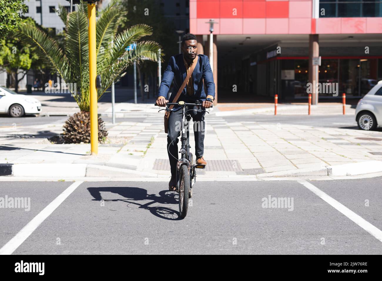 Homme afro-américain à vélo traversant la route Banque D'Images