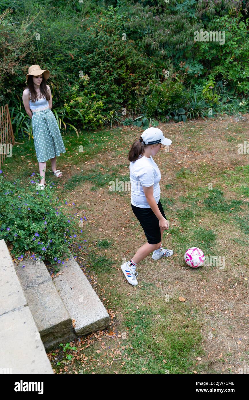 Deux jeunes femmes jouant au football dans le jardin pendant les vacances d'été dans le Dorset Banque D'Images