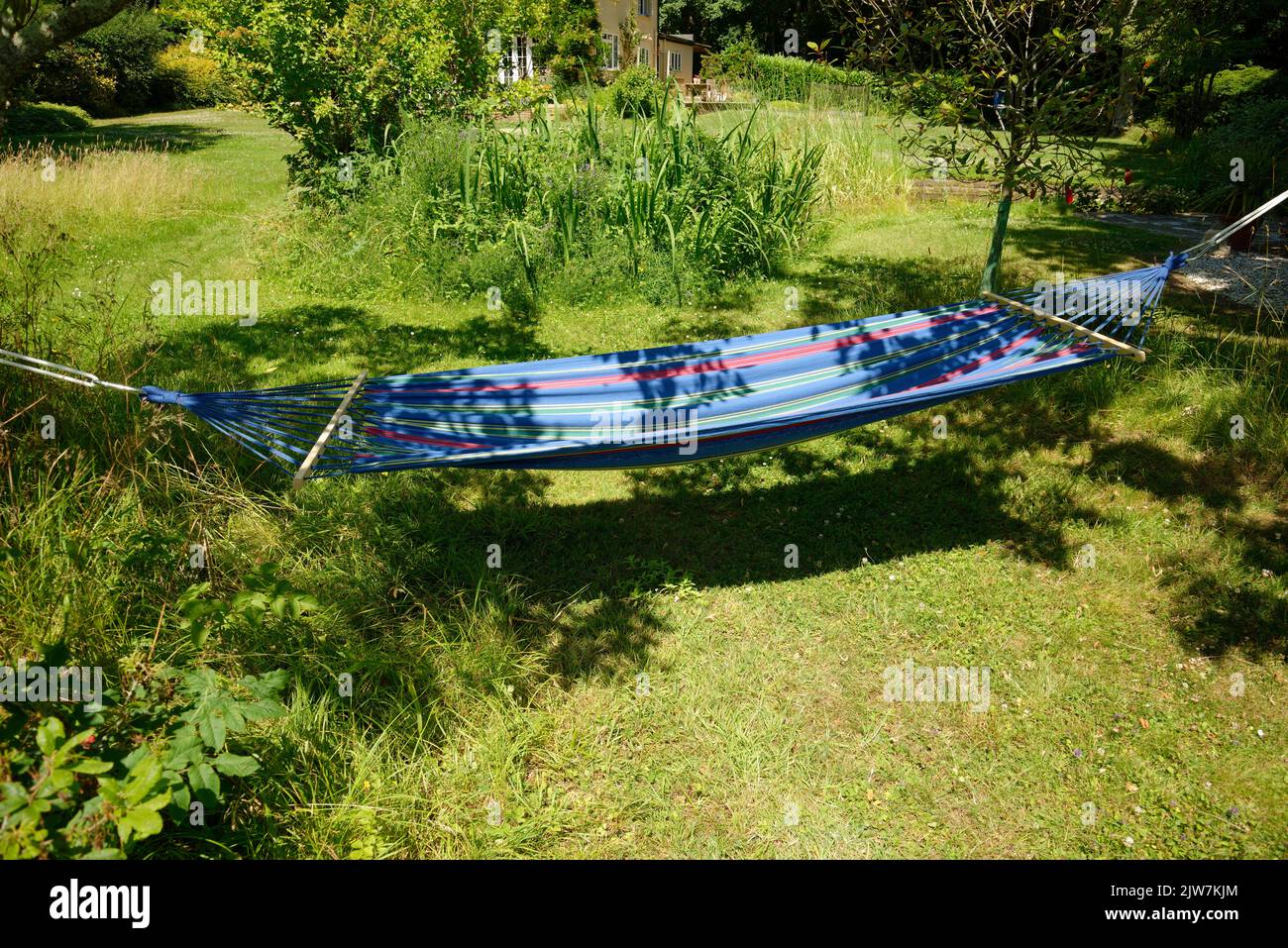 Un hamac de jardin en été. Détendez-vous dans un confort suspendu dans un hamac en tissu doux aux rayons du soleil. Banque D'Images