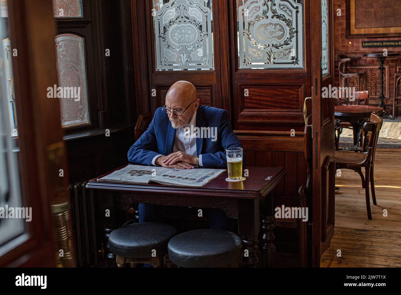 Fermeture massive des pubs en raison de l'augmentation des factures d'énergie. Costomer lisant le journal avec un verre de pinte à la Boleyn Tavern, West Ham , Londres , Royaume-Uni. Banque D'Images