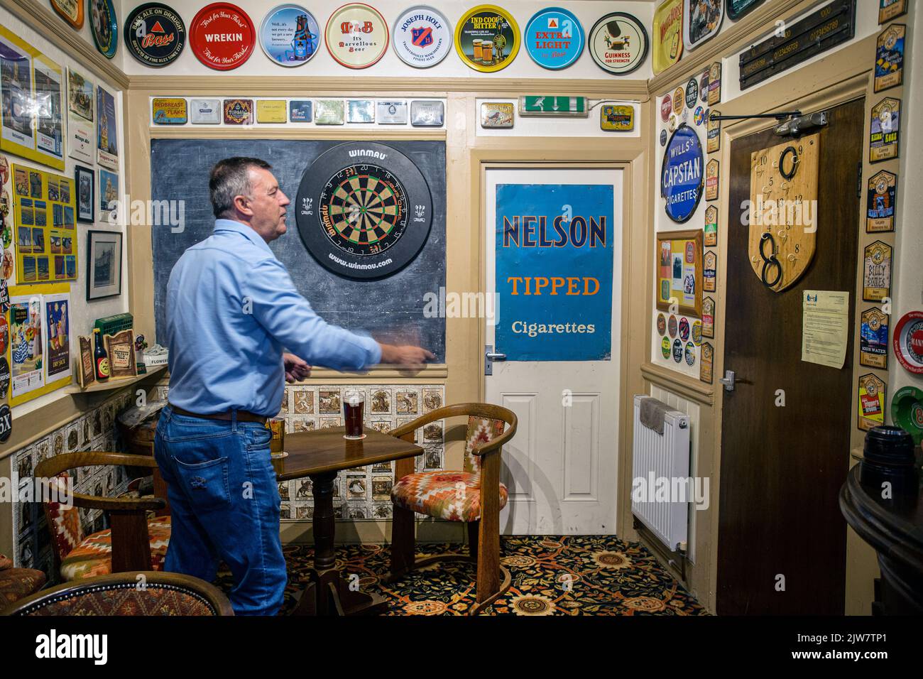 The Mason Arms , Patron joue un vieux jeu d'anneaux dans lesquels des anneaux en caoutchouc sont projetés sur des crochets numérotés sur un panneau mural Banque D'Images