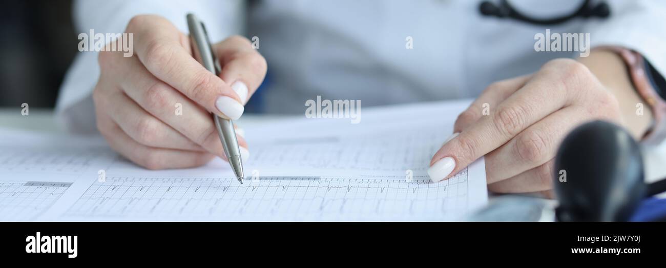 Médecin cardiologue examinant le cardiogramme du patient sur papier en clinique de près Banque D'Images
