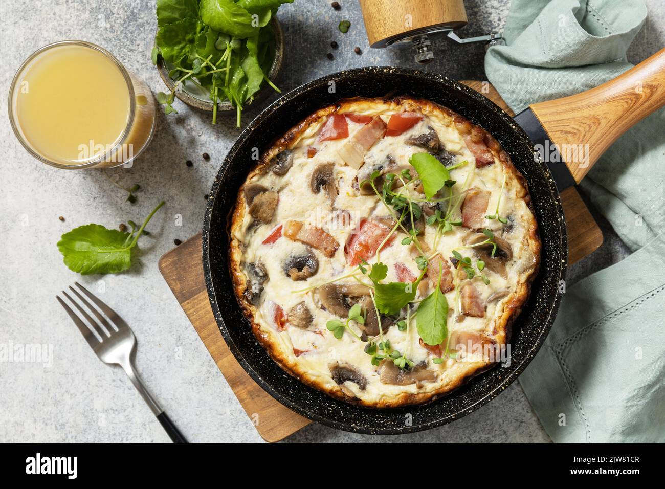 Petit-déjeuner italien. Omelette rustique (frittata) avec champignons et bacon sur une poêle en fonte. Vue de dessus. Banque D'Images