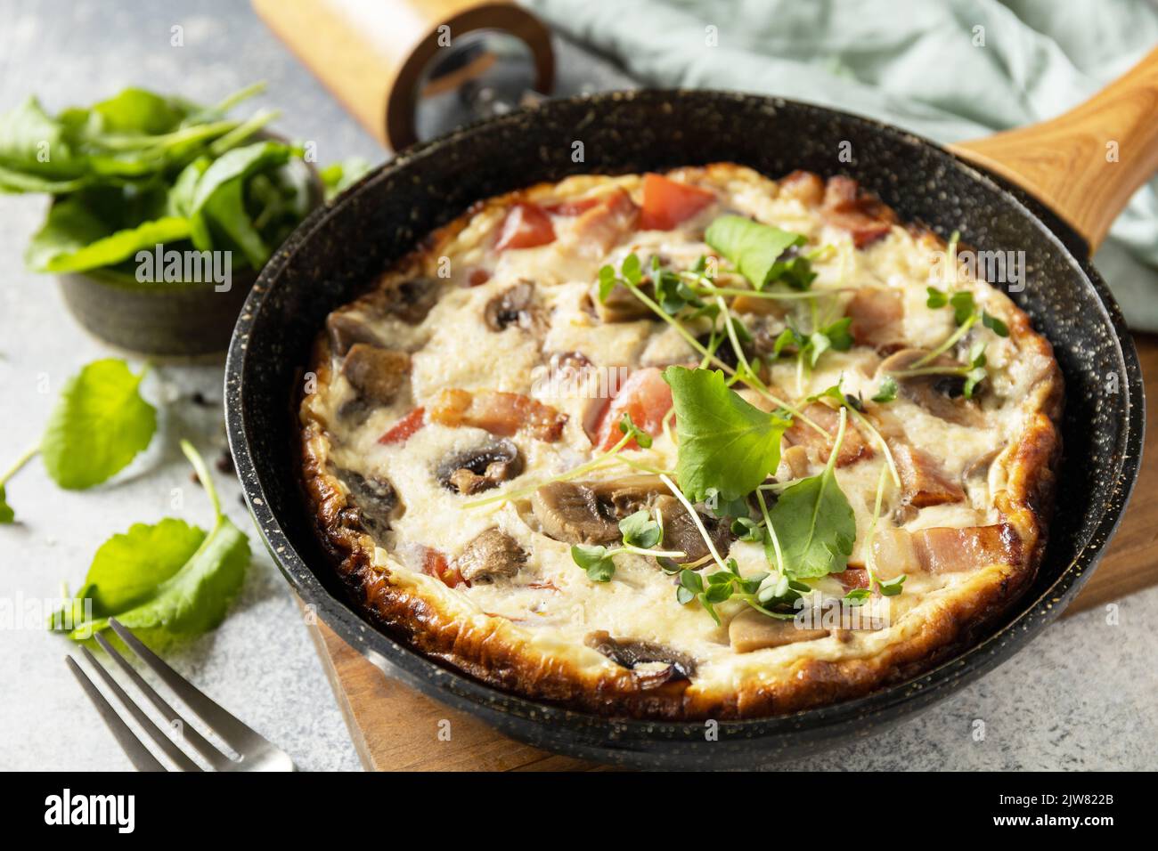 Petit-déjeuner italien. Omelette rustique (frittata) avec champignons et bacon sur une poêle en fonte. Banque D'Images