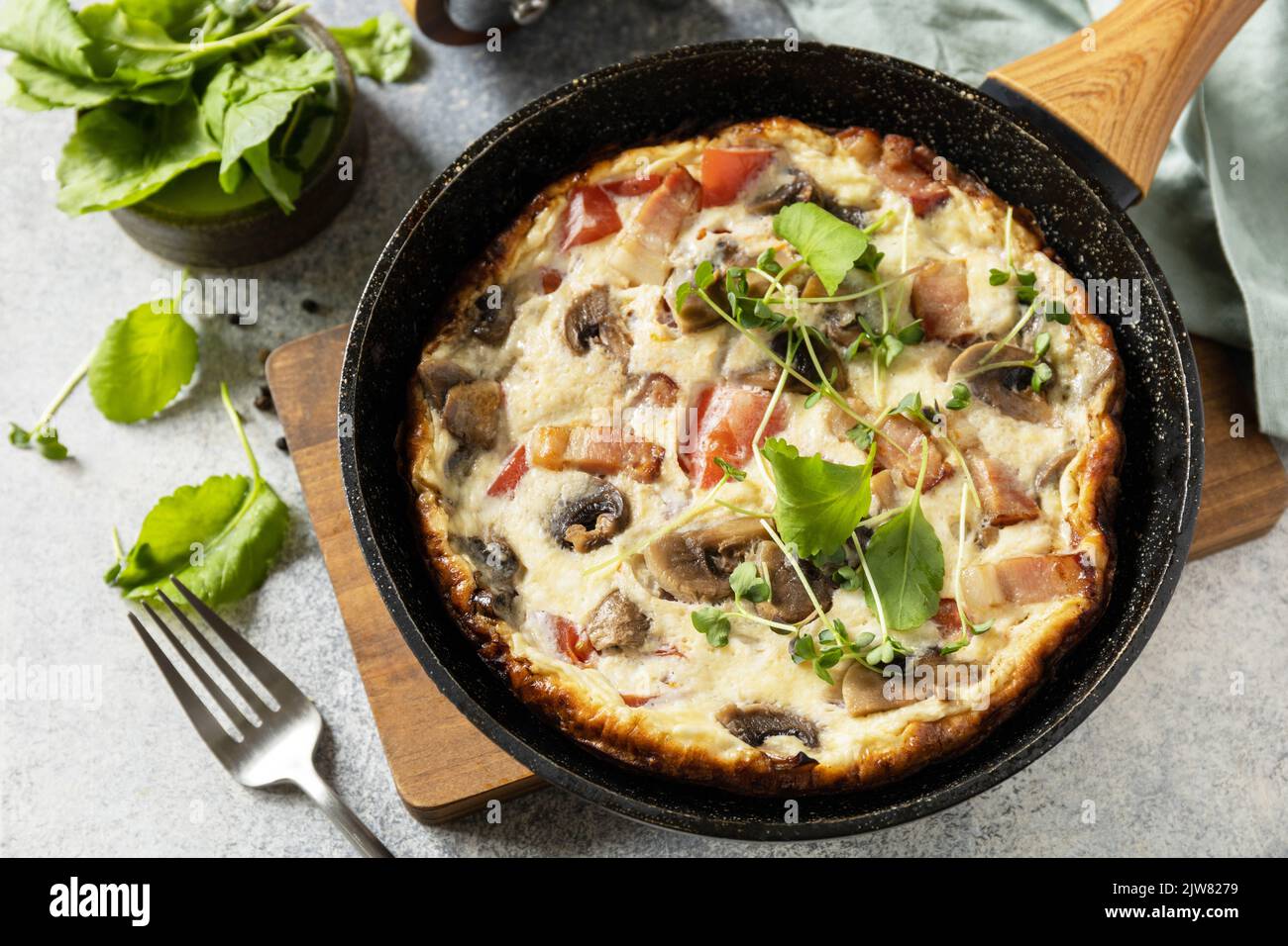 Omelette rustique (frittata) avec champignons et bacon sur une poêle en fonte. Petit-déjeuner italien. Banque D'Images