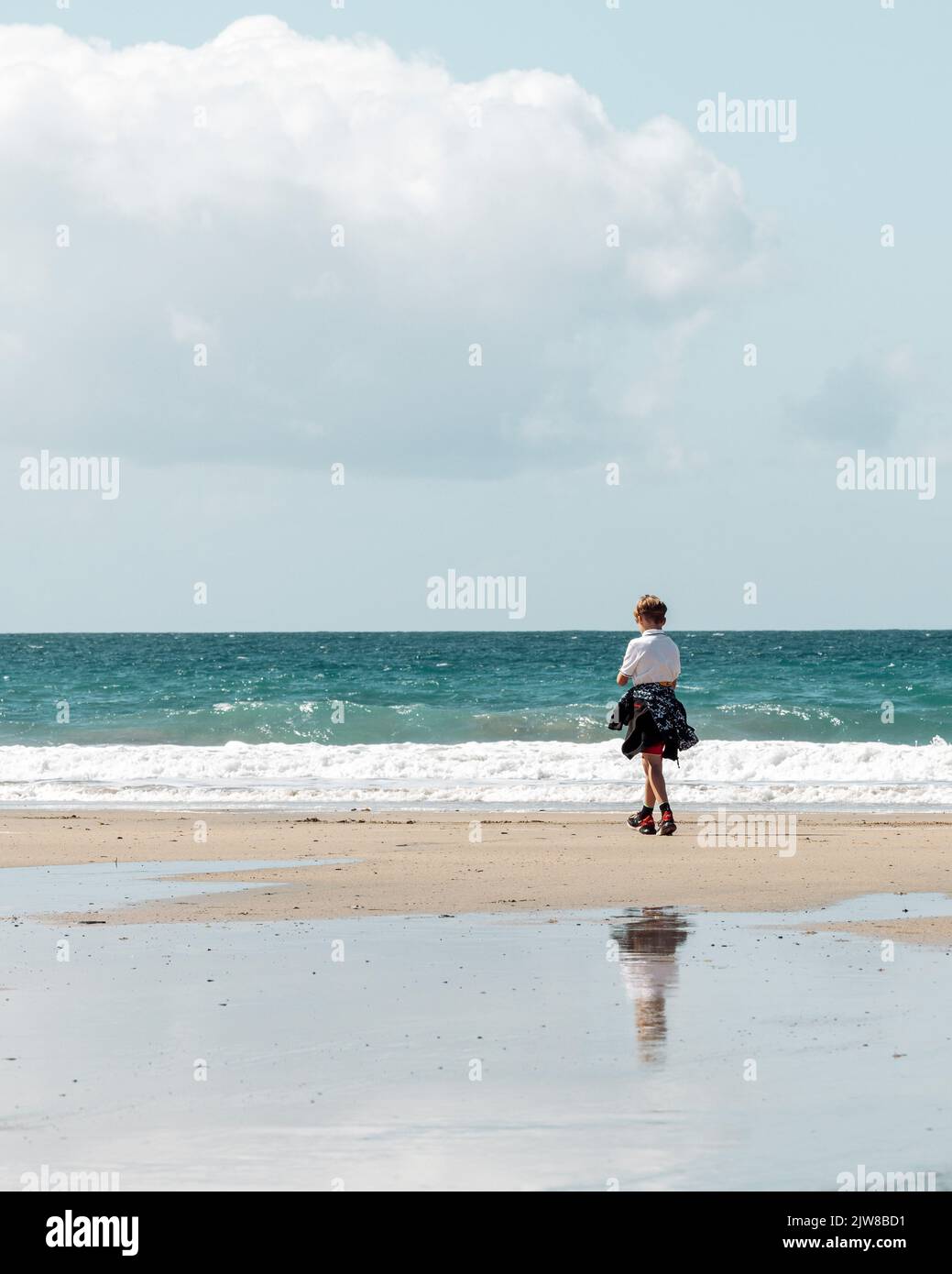Un jeune homme à explorer la plage de sable de PRAA Cornwall. Banque D'Images