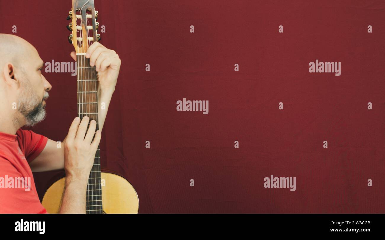 Instrument de musique à cordes. Guitariste masculine charismatique mature. Guy avec barbe tient de la guitare. Homme barbu dans une chemise rouge. Interprète musical de la musique. Banque D'Images