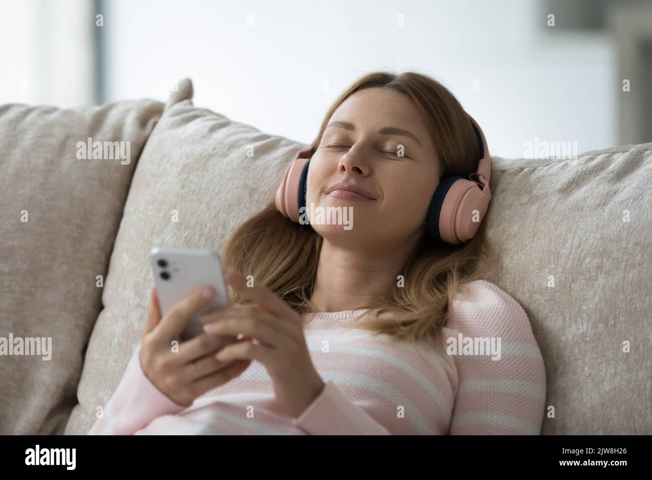Décontracté insouciante jeune femme utilisateur de gadget porter de grands écouteurs Banque D'Images