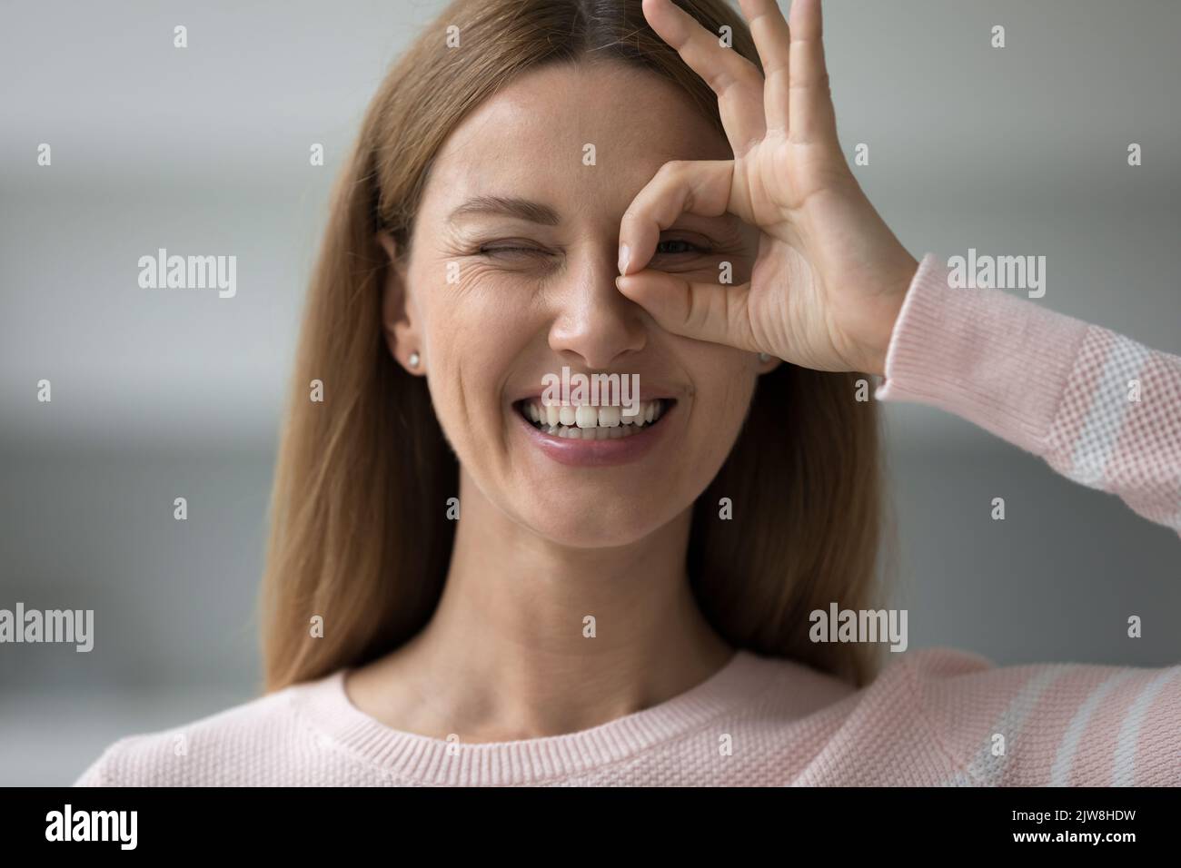 Gaie femme adulte regardant la caméra à travers main doigt binoculaire Banque D'Images