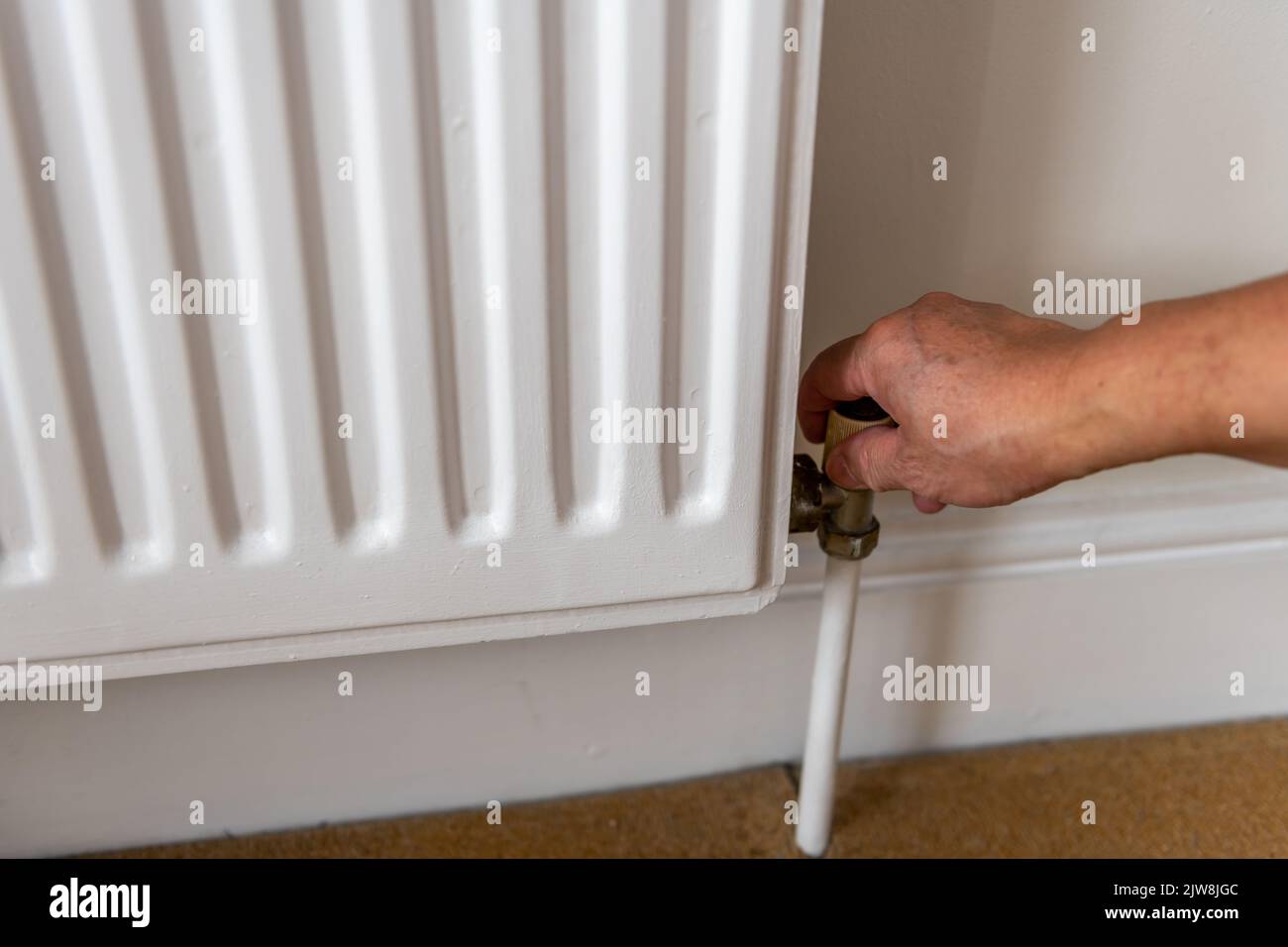 Personne qui éteint le radiateur de chauffage pour réduire les coûts énergétiques. Banque D'Images