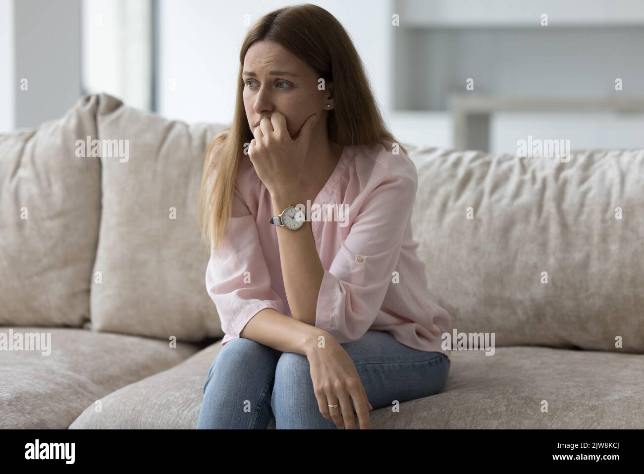 Malheureux déprimé jolie femme assise sur le canapé à la maison Banque D'Images
