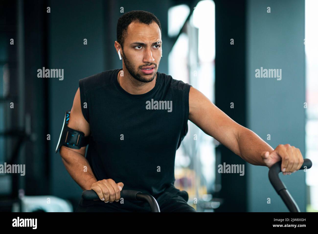 Homme noir motivé utilisant un vélo elliptique pendant l'entraînement à la salle de gym Banque D'Images