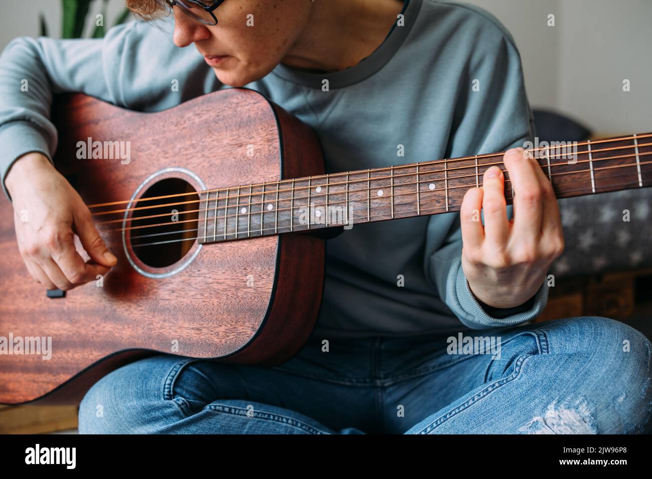 Femme aux cheveux courts aime jouer de la guitare à la maison. Leçons de musique pour adultes Banque D'Images