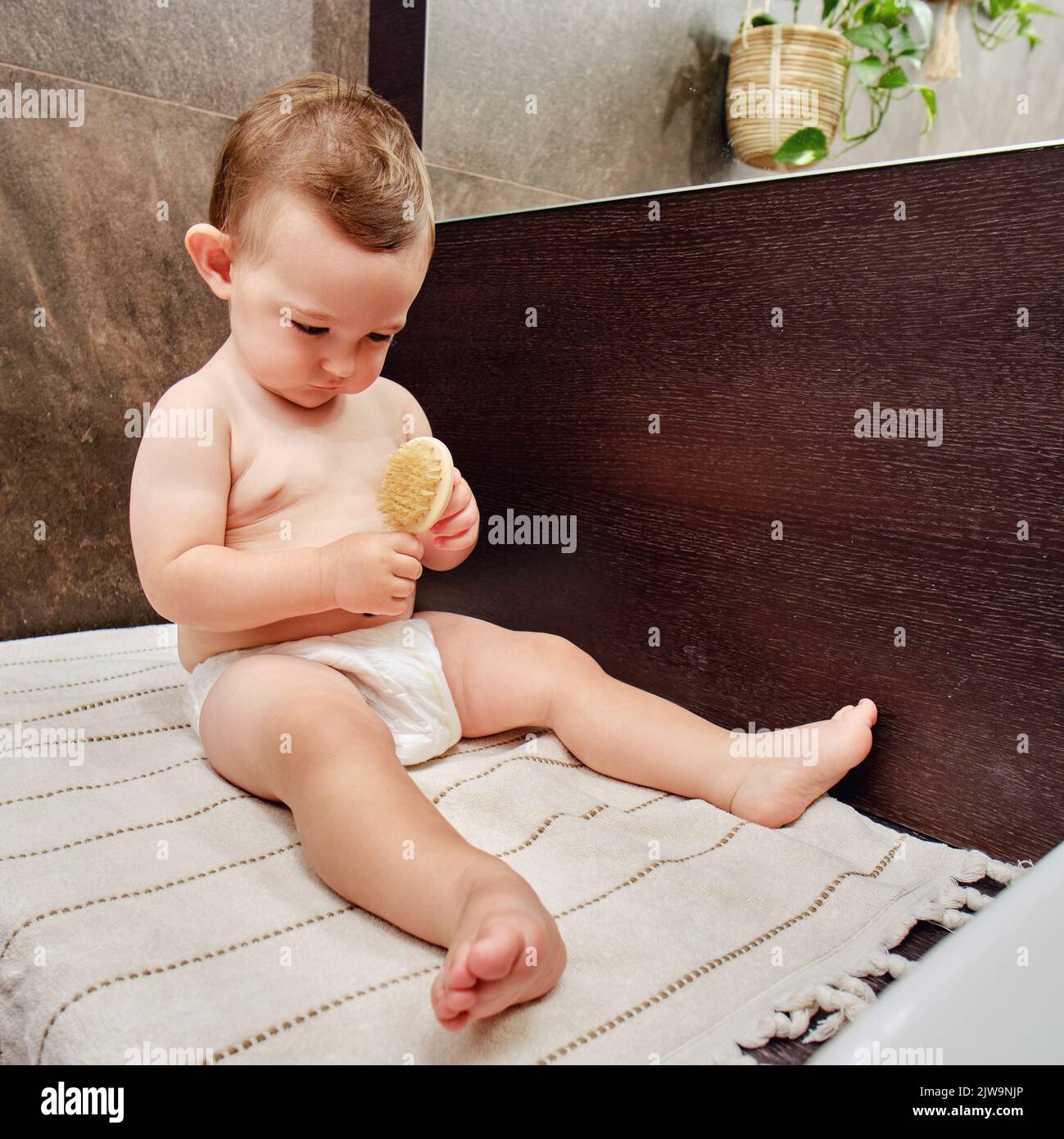 Portrait d'un bébé heureux avec un peigne dans la salle de bains près du miroir. Bébé garçon assis sur une serviette. Enfant d'un an Banque D'Images Portrait d'un bébé heureux avec un peigne dans la salle de bains près du miroir. Bébé garçon assis sur une serviette. Enfant d'un an Banque D'Images
