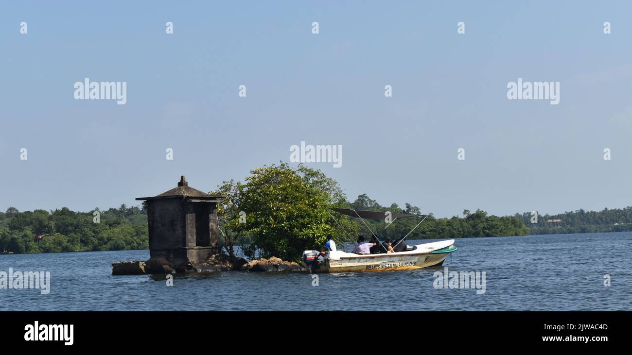 Le plus petit îlot du lac Madu Ganga est appelé « Satha Paha Doowa ». “Paha” se traduit par “cinq”, alors que “Satha” signifie “cent”. Selon la tradition locale, l'îlot avait été acheté pour cinq cents. Mais d'autres disent, il a obtenu son nom en raison de la forme ou de la petite taille qui ressemble à une petite pièce. L'île de Nonough-cent-Island est assez grande pour porter un temple. Le sanctuaire est dédié à Kataragama, une déité vénérée par les bouddhistes cinghalais, les hindous tamouls et les animistes de Weddah. D’une certaine manière, c’est un Devale, un sanctuaire bouddhiste pour une déité hindoue. Sri Lanka. Banque D'Images