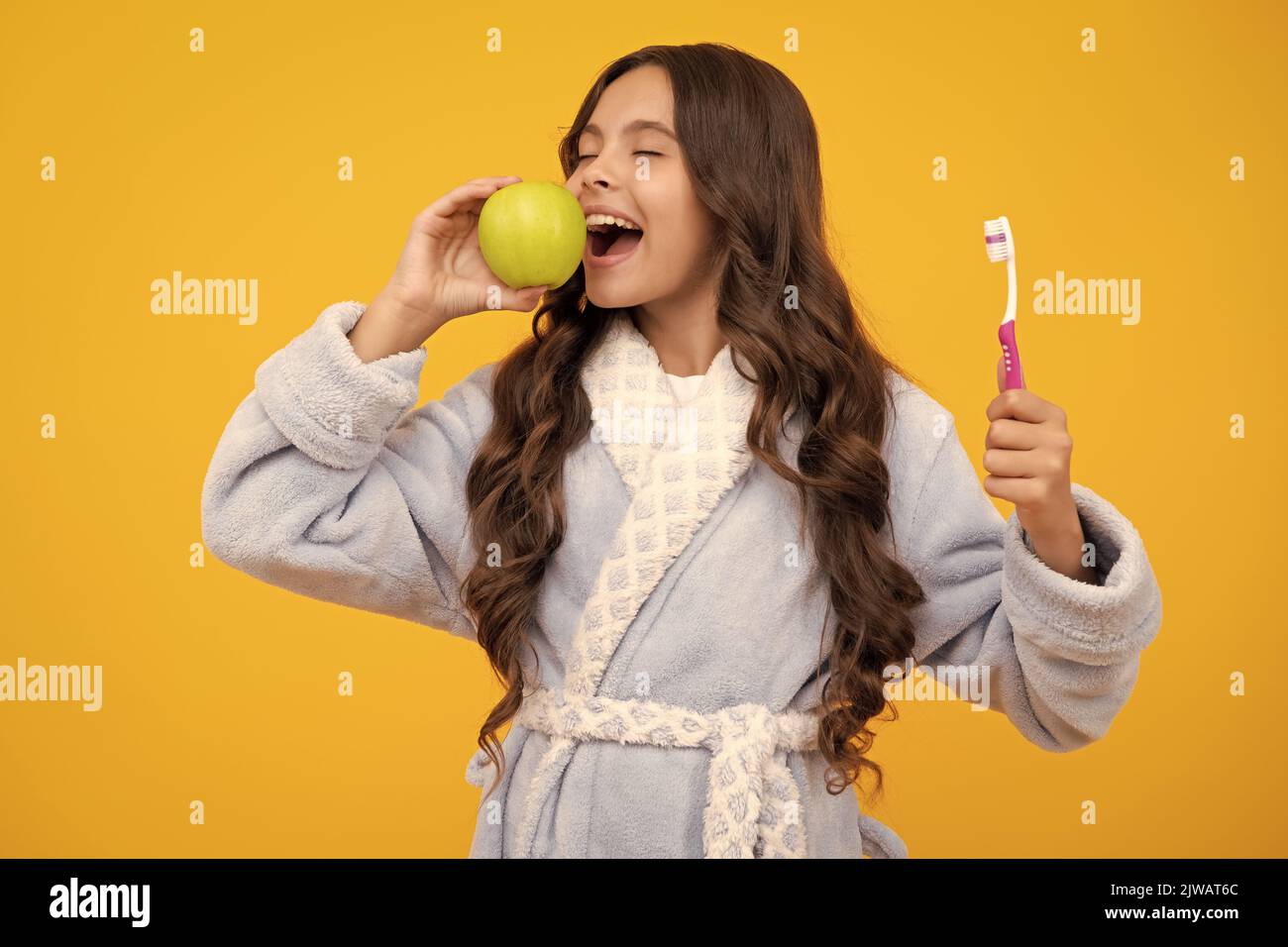 Vitamines de pomme pour des dents saines. Portrait de la jeune fille caucasienne tient une brosse à dents se brossant ses dents, routine du matin, hygiène dentaire, isolé dessus Banque D'Images