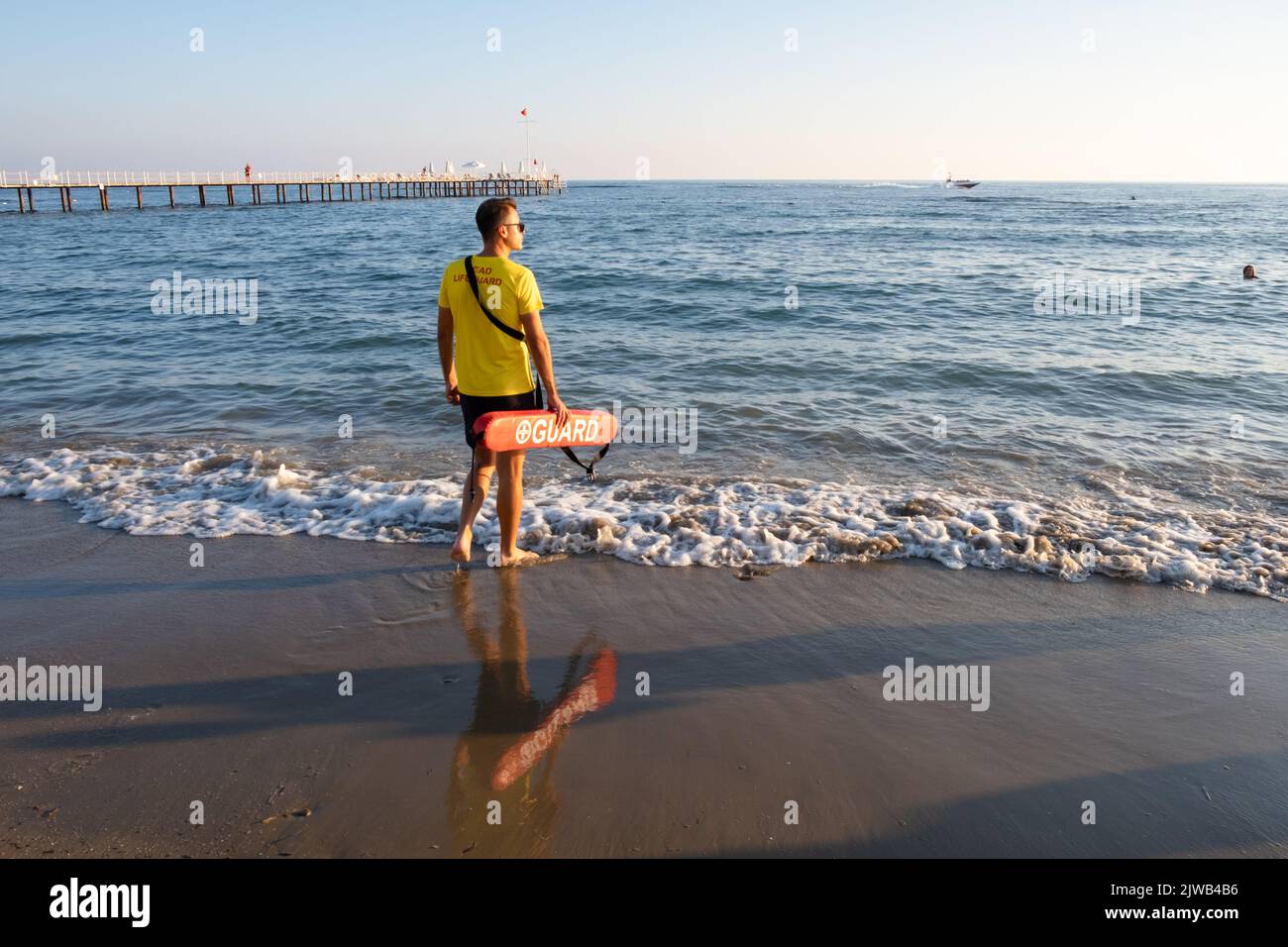 Maître nageur sur la plage méditerranéenne, observant les gens dans l'eau. Sécurité pendant la natation, beau brunette homme maître nageur sur la plage. Banque D'Images