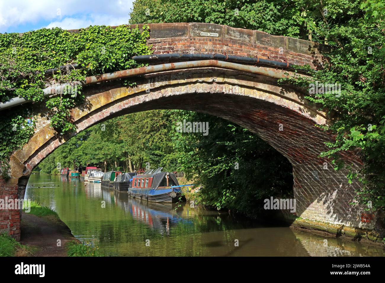 Été dans le village de Moore, pont Moore au-dessus du canal Bridgewater, Halton, Cheshire, Angleterre avec des barges de canal amarrés Banque D'Images