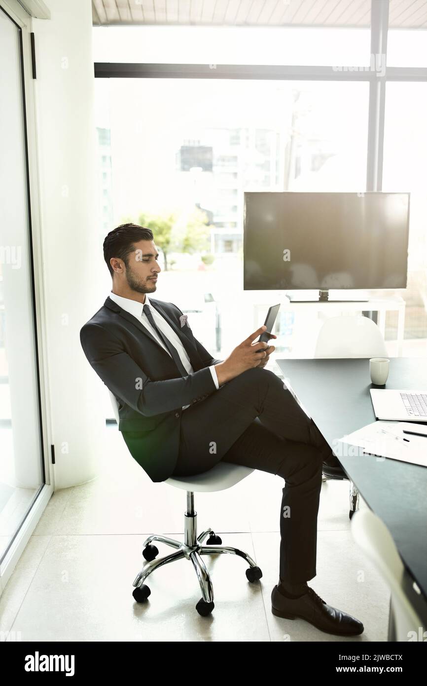 S'assurer que son entreprise est plus mobile. Un homme d'affaires utilisant sa tablette tout en étant assis dans un bureau. Banque D'Images