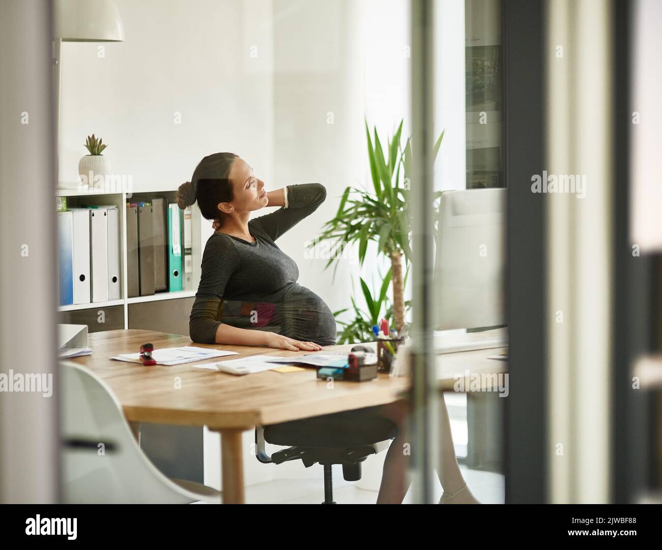 Laisse ne peut pas venir assez vite. Une femme d'affaires enceinte dans l'inconfort dans son bureau. Banque D'Images