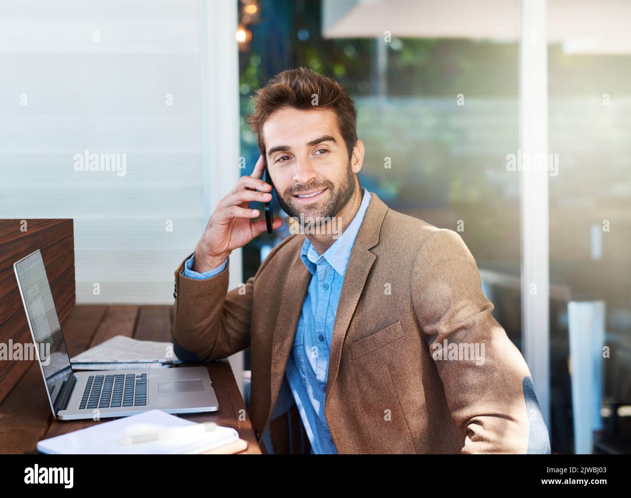 Pas de bureau Pas de problème. un jeune entrepreneur parlant au téléphone dans un café. Banque D'Images