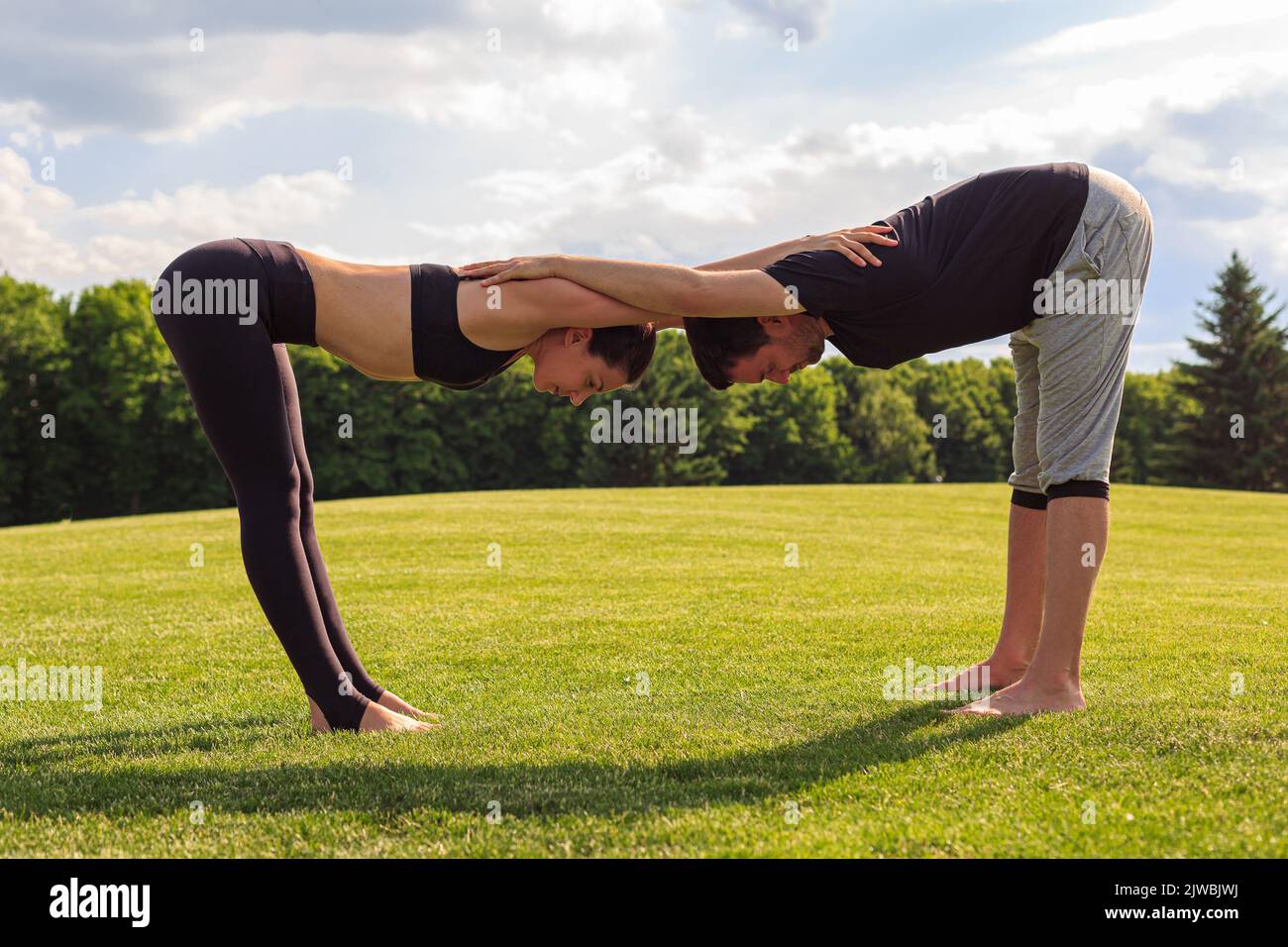 Jeune couple en bonne santé faisant un exercice de yoga acrobatique dans le parc Banque D'Images