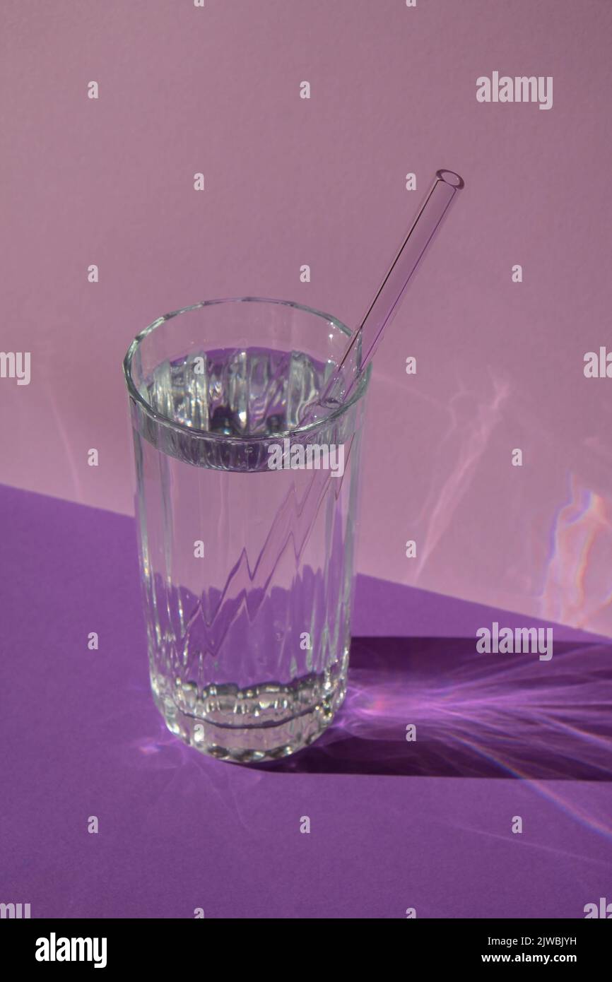 Pailles en verre réutilisables en verre avec eau sur fond violet violet ensemble de pailles écologiques avec brosse de nettoyage. Concept sans déchets, sans plastique. Style de vie durable. Vie sans déchets peu de déchets Banque D'Images