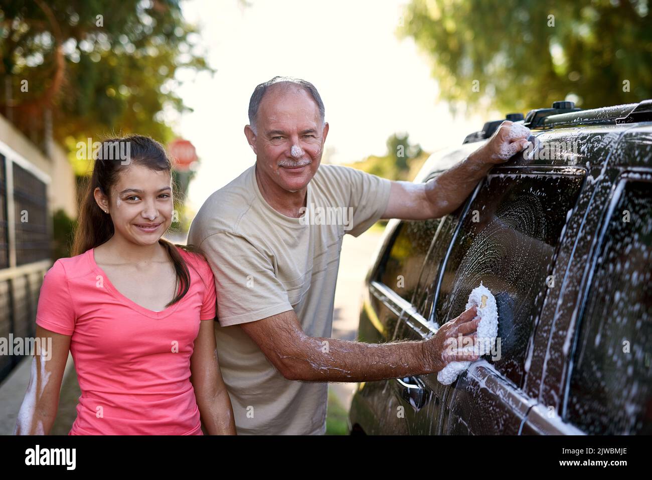La voiture sera à nouveau flambant neuve lorsque vous aurez terminé. Portrait d'un père et d'une fille lavant une voiture ensemble à l'extérieur. Banque D'Images
