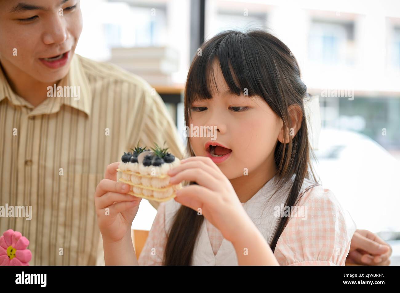 Adorable petite fille asiatique aimez manger du gâteau avec son père ou frère âgé au café-restaurant. Concept enfants avec desserts Banque D'Images