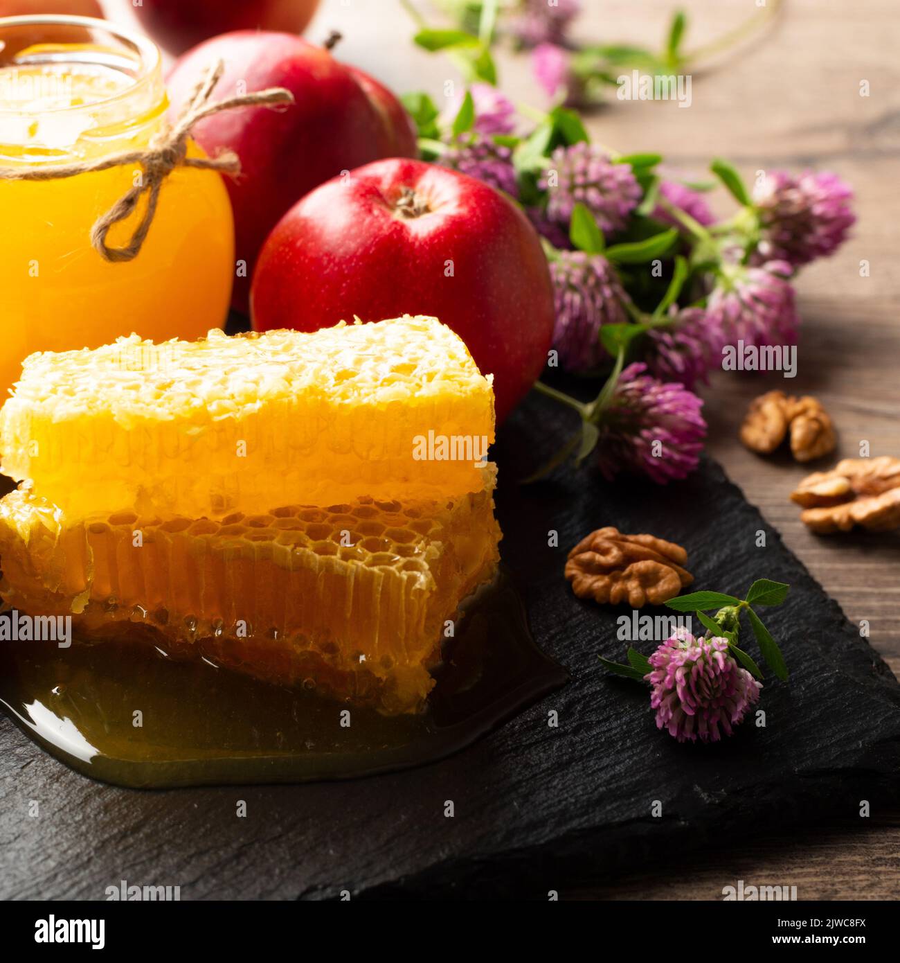 Pot Mason avec miel, nid d'abeille, pommes rouges et noix sur la table de cuisine Banque D'Images